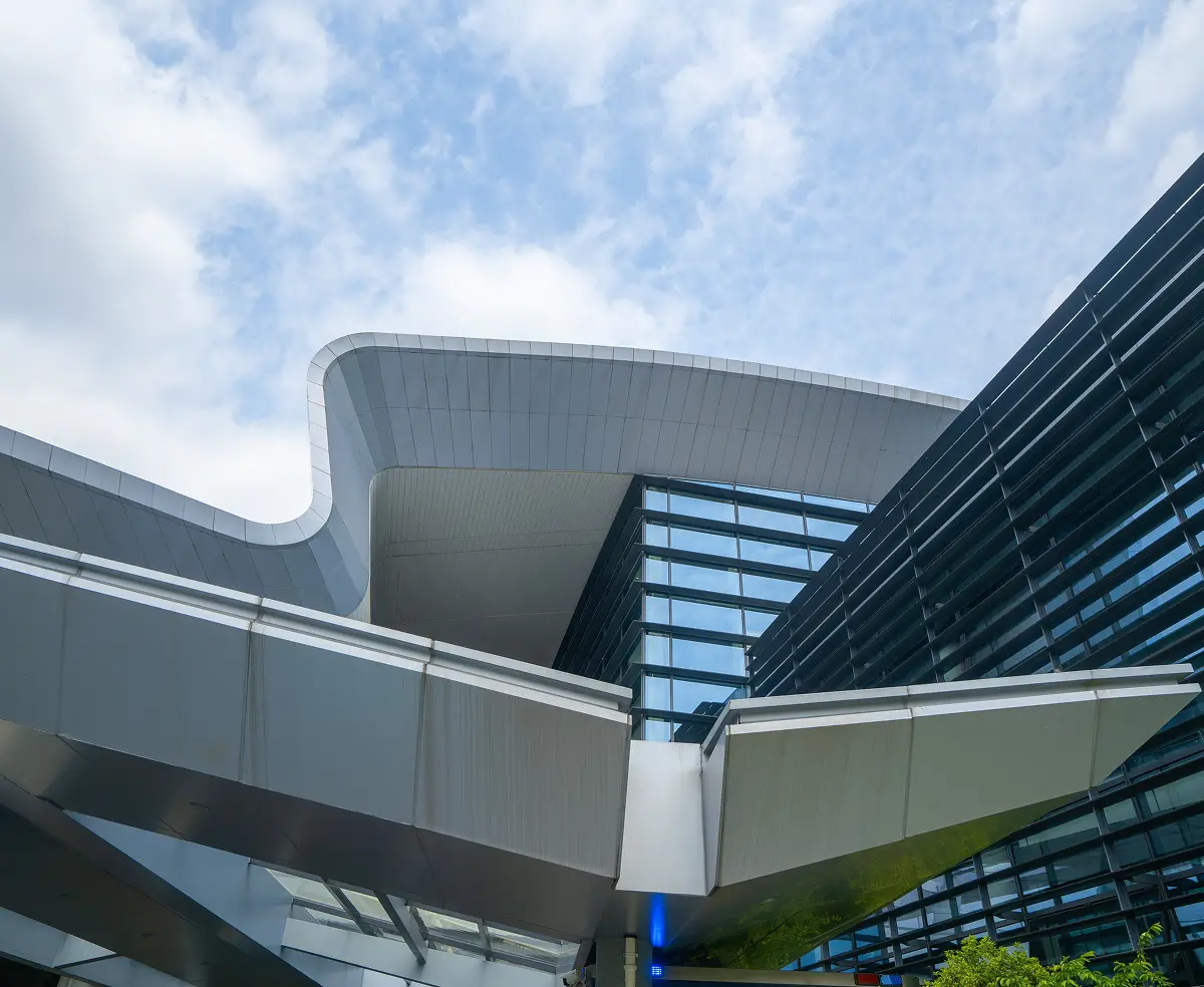 Futuristic building with sleek, angular metallic and glass structures against a partly cloudy sky, conveying a modern and innovative feel.